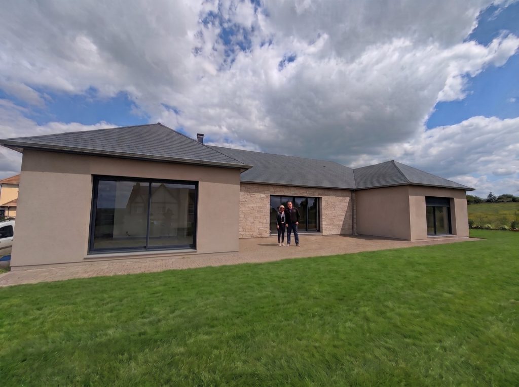 Maison de plain-pied neuve et ses propriétaires devant la terrasse